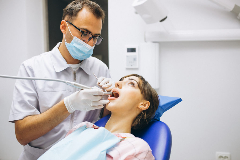 paciente mujer joven en el consultorio de un dentista que le explica la diferencia entre endodoncia y corona