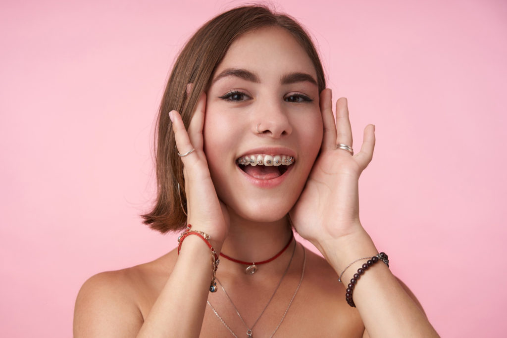 mujer joven latina con brackets feliz por que ya no necesitara una operacion para asimetría facial