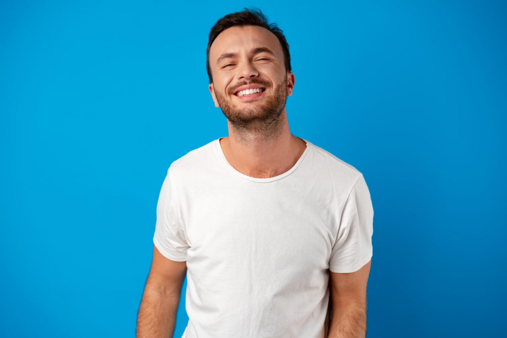 happy smiling handsome man against blue background knowing the differences between ceramic braces before and after