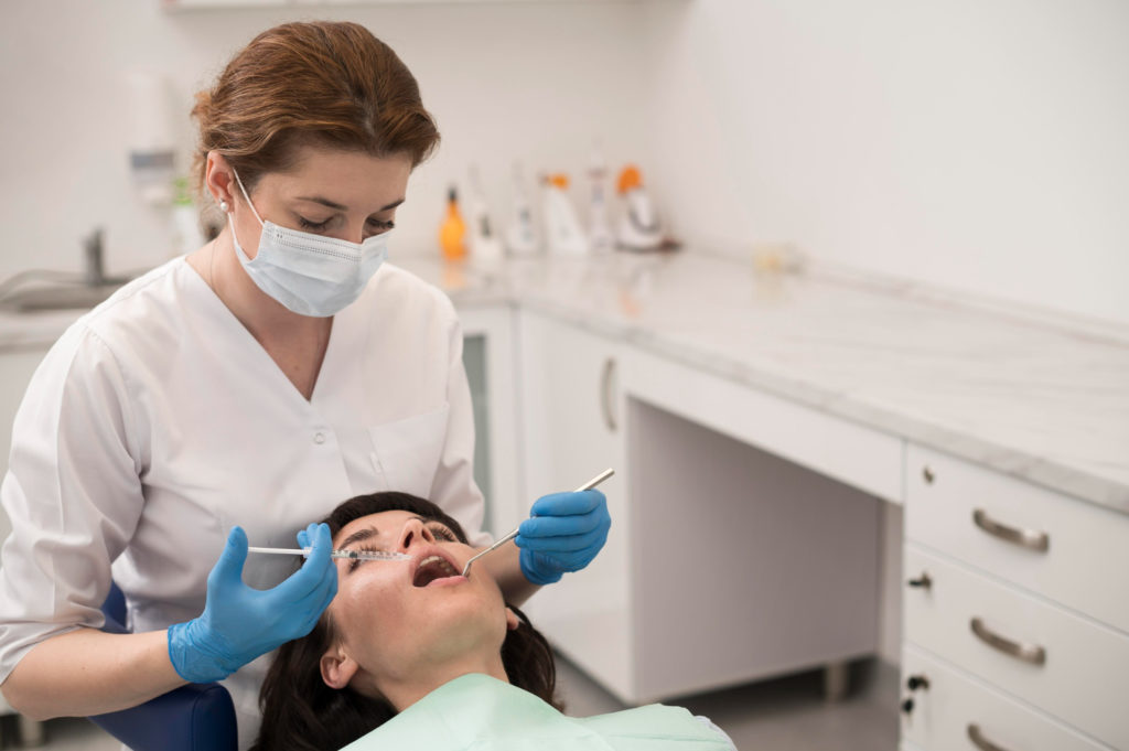 dentist in her clinic with a patient explaining how long does it hurt after tooth extraction