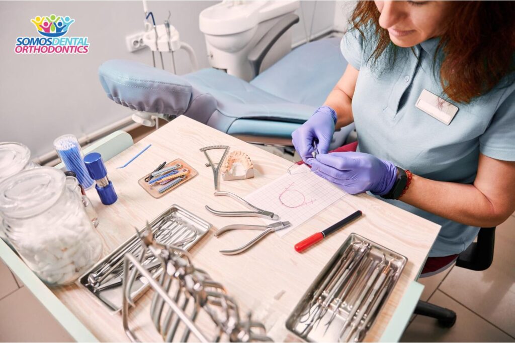 female orthodontist working in dental office getting ready to clean gum stuck in braces