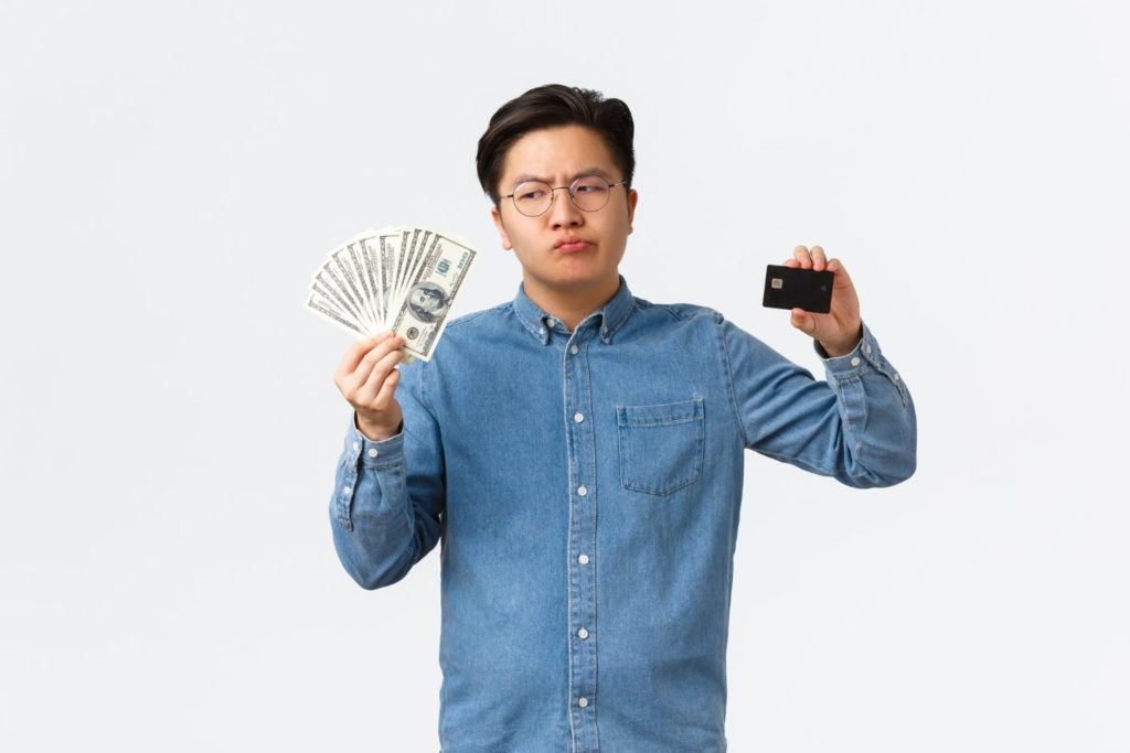 perplexed asian businessman glasses holding cash money looking doubtful money thinking why are braces so expensive