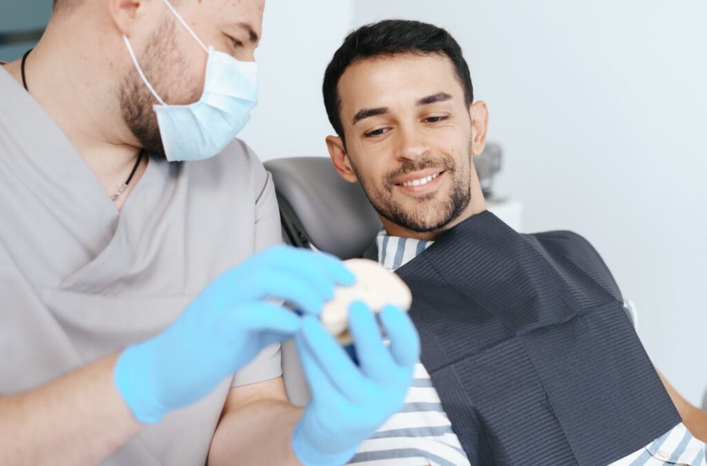 male dentist explaining purpose of rubber bands on braces