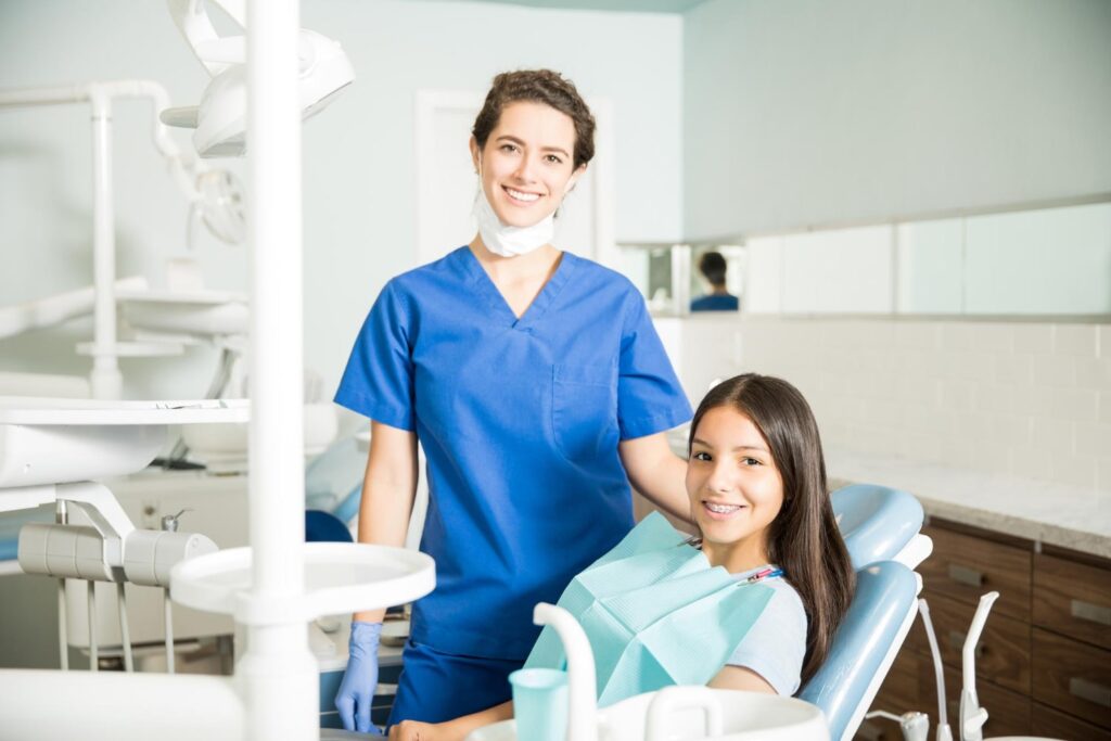 portrait smiling young female dentist standing by teenage girl clinic knowing the best age for braces