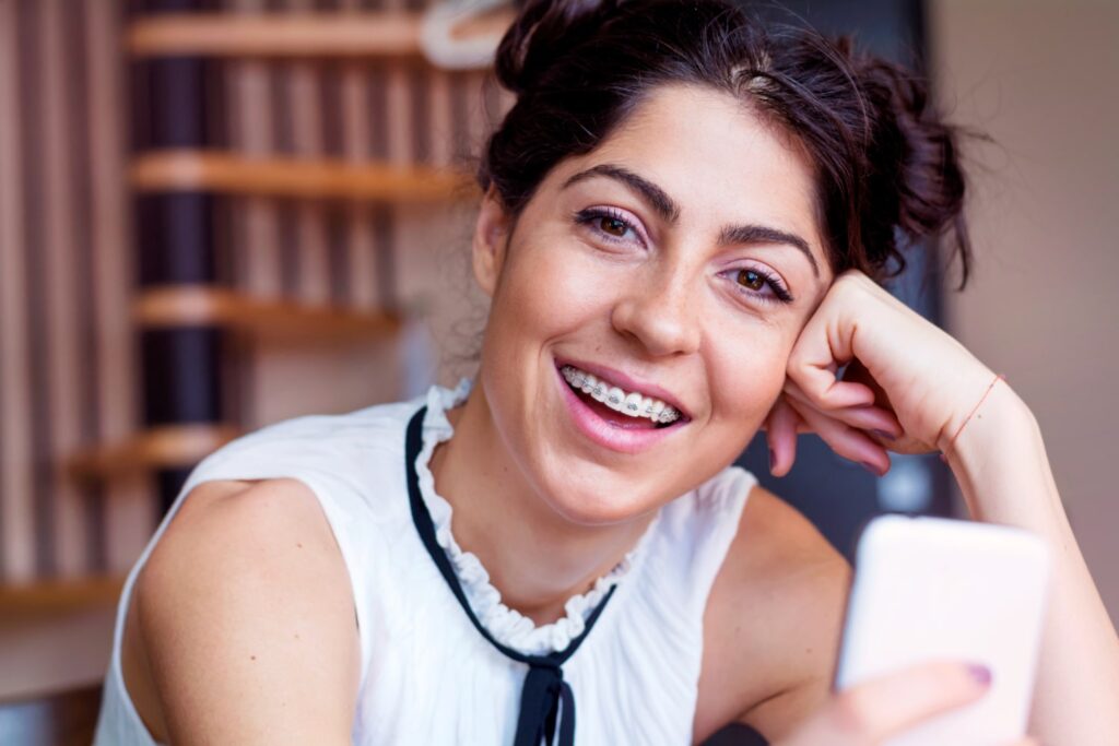 close up happy girl with her mobile happy to know if can braces change your jawline