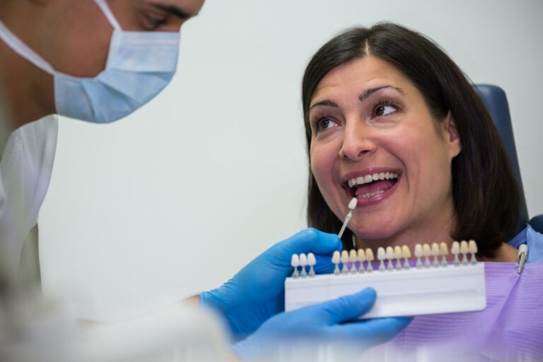 dentist examining female patient with teeth shades explaining dental crown cost without insurance