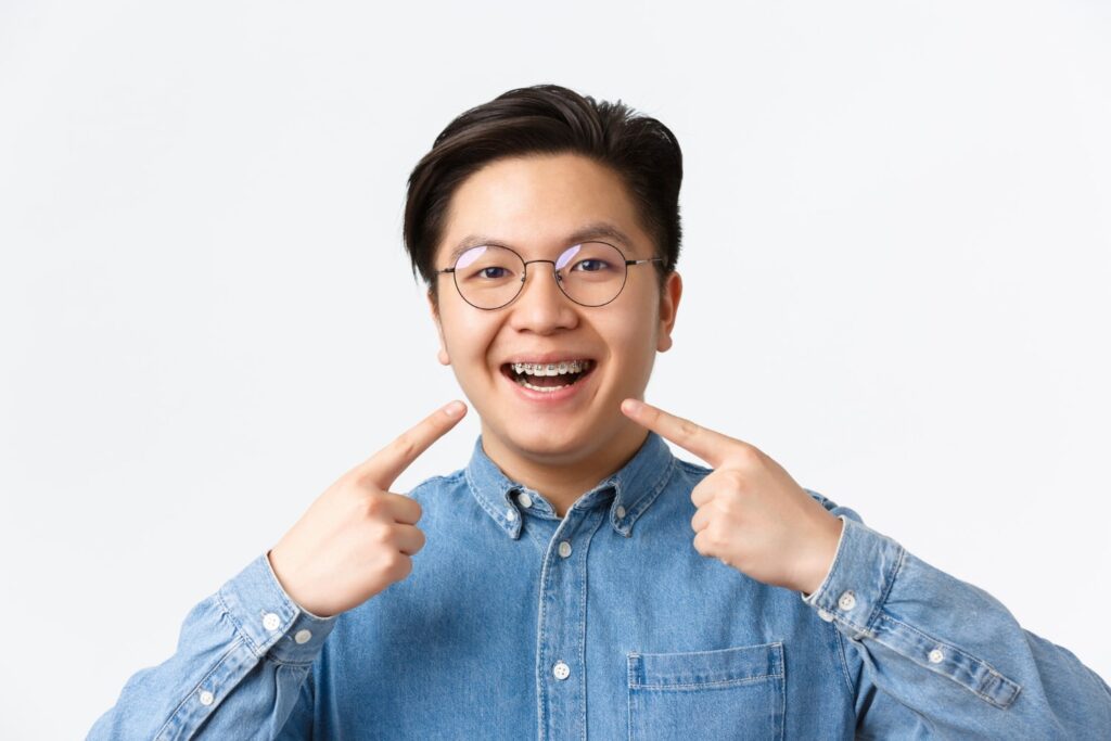 satisfied asian guy smiling happy pointing his dental braces standing white background happy to know if do braces change your jaw