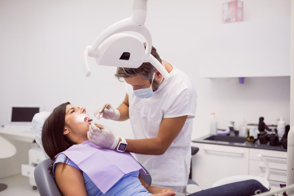 dentist examining female patient teeth and explaining if can orthodontist fill cavities