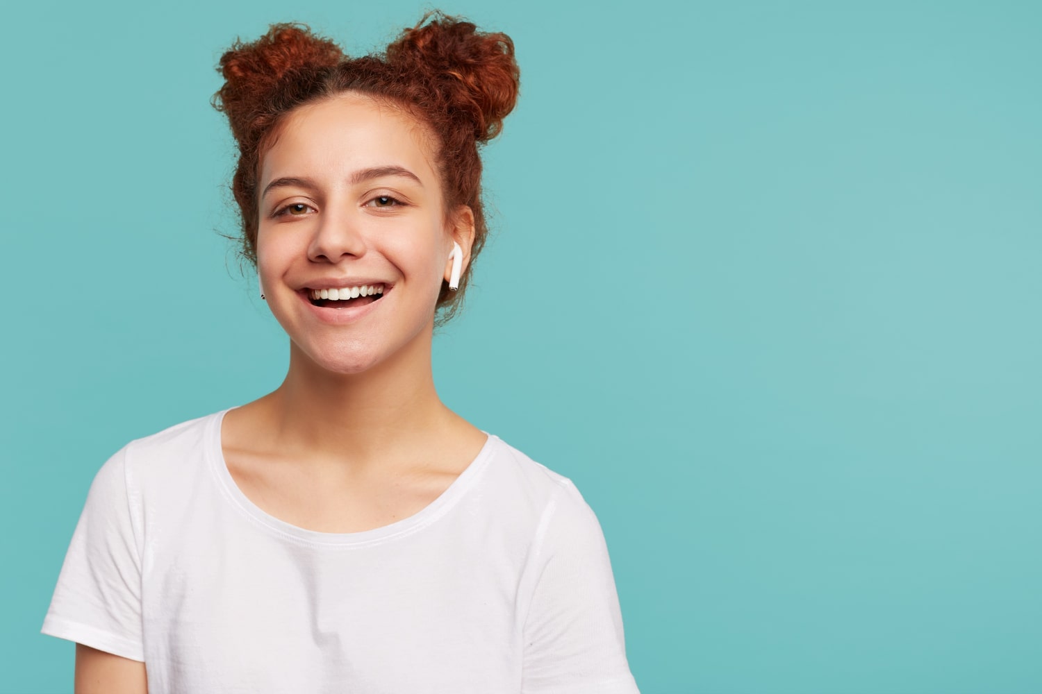 positive young pretty curly brunette woman with bun hairstyle and braces happy to know how long do you need to wear braces