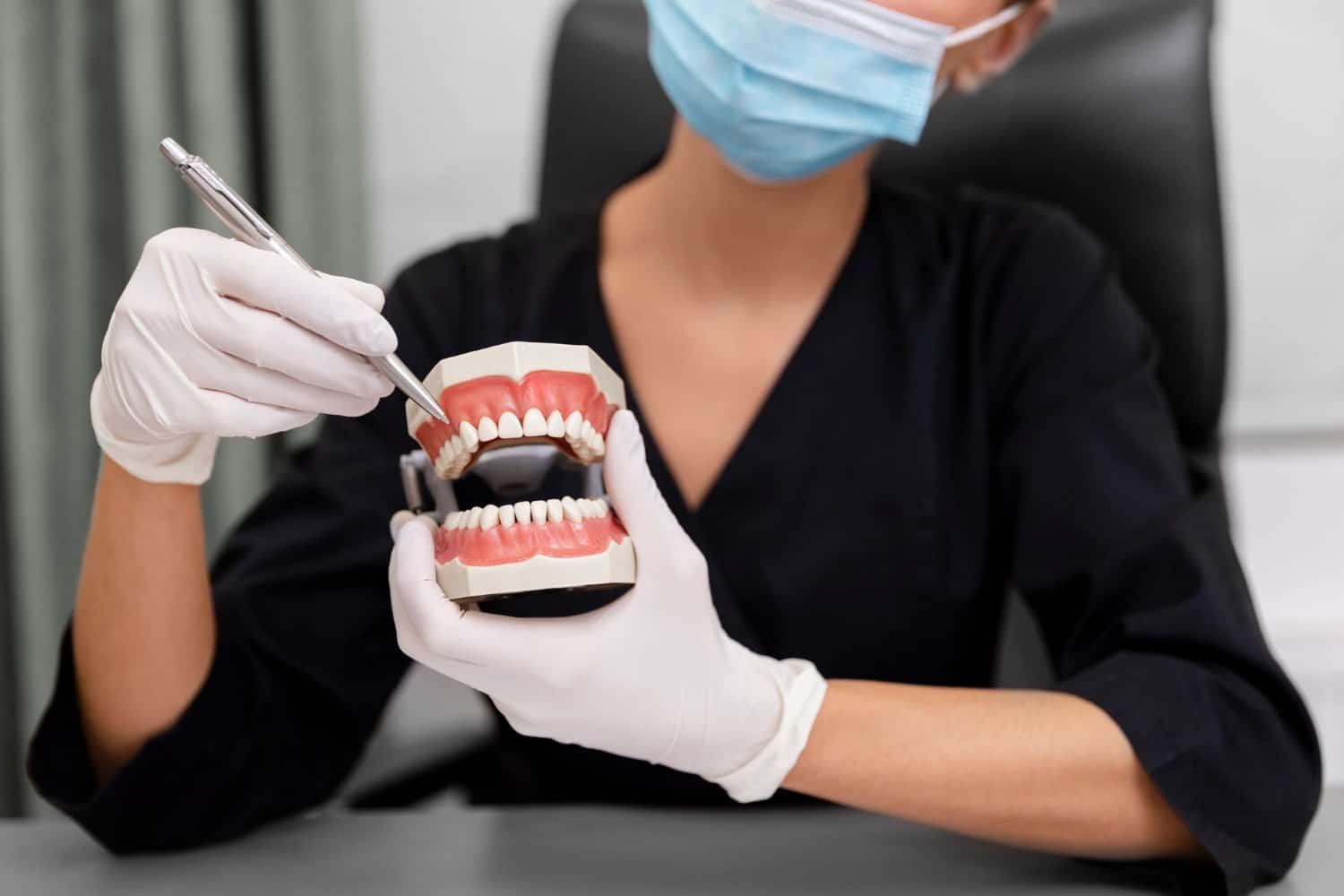 close up dentist holding teeth model to explain what does a dental crown look like