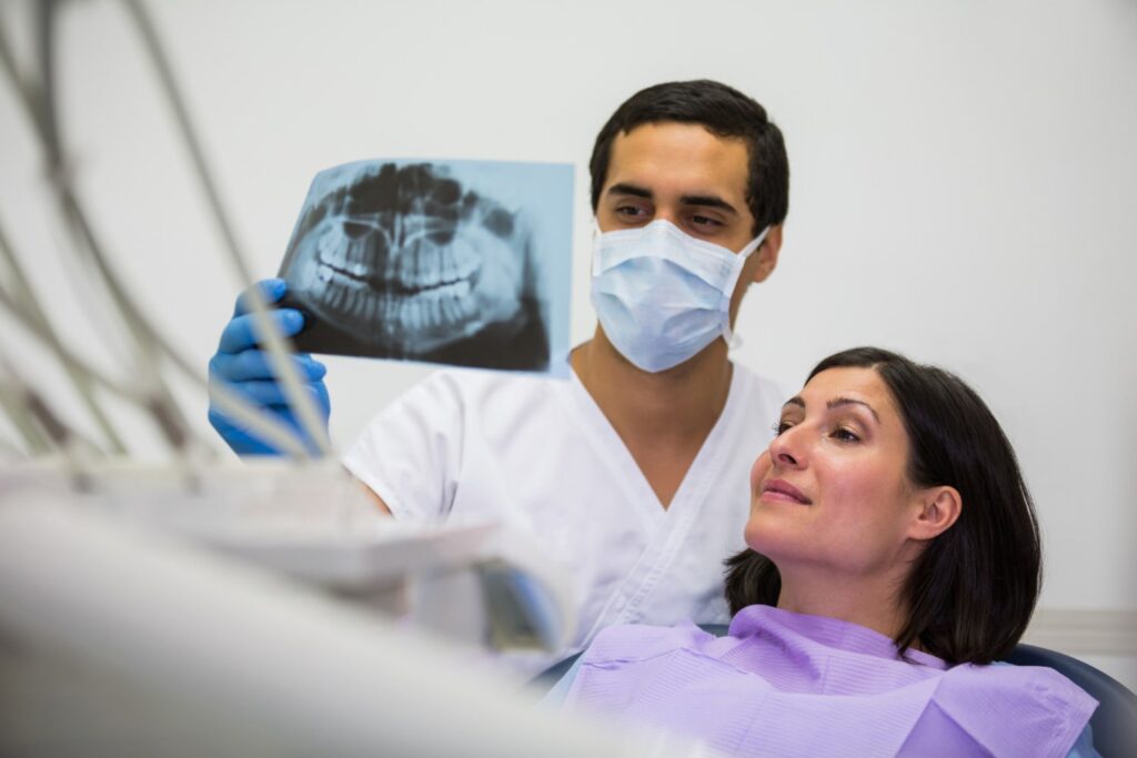 young male dentist examining x ray with female patient explaining root canal cost in dallas without insurance