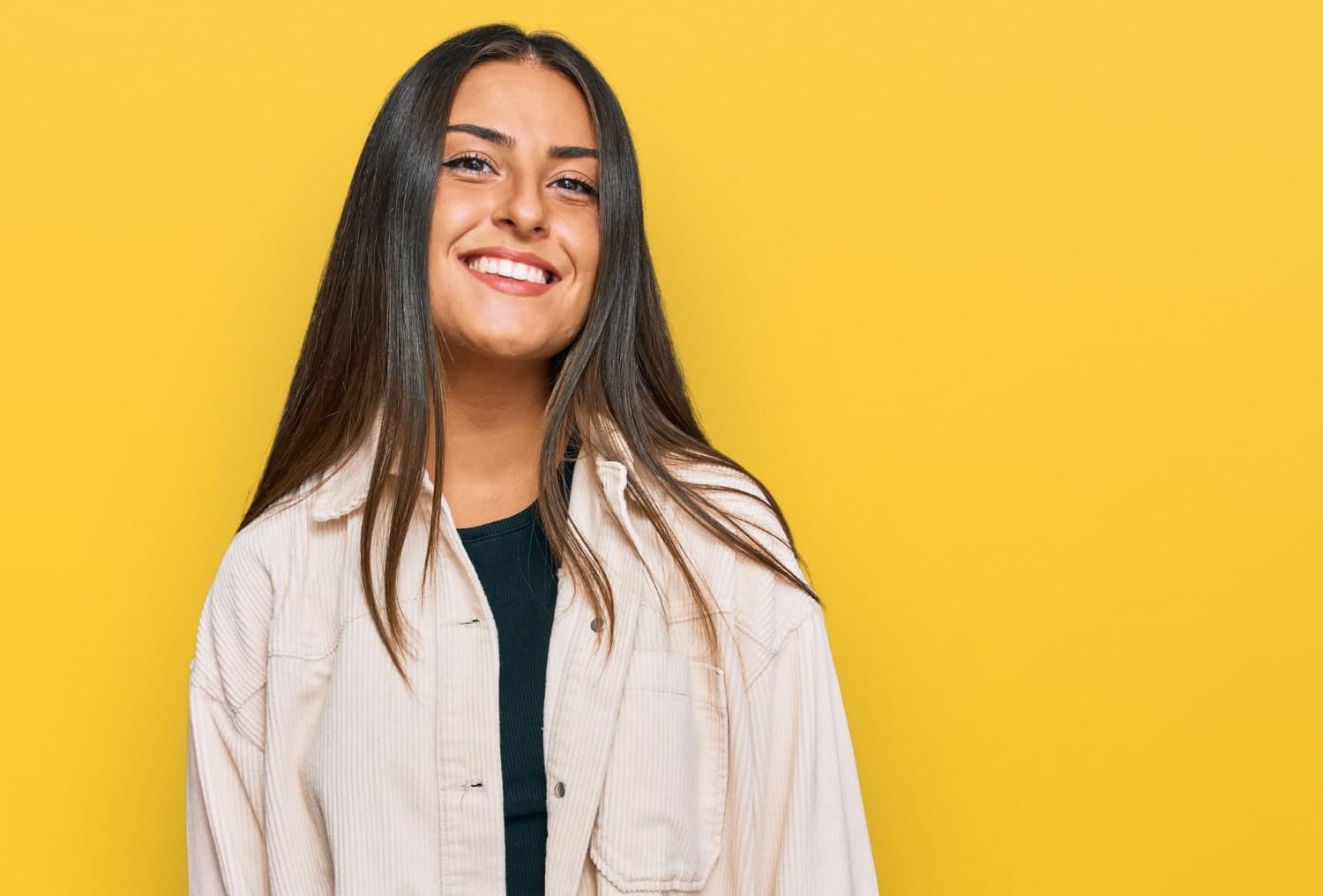 Beautiful Hispanic woman in casual clothing standing happily, smiling with a confident smile showing teeth wondering about teeth shifting after braces