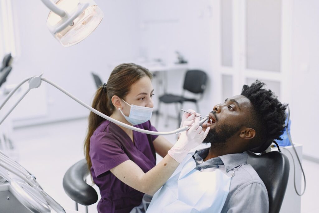 young african american man guy visiting dentists office prevention oral cavity man famale doctor while checkup teeth