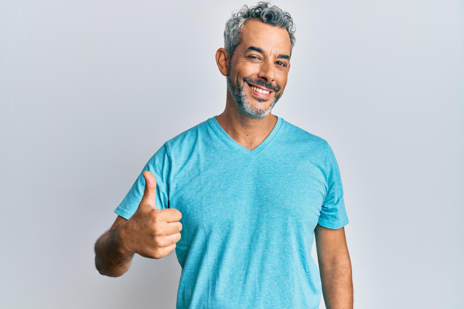 Middle age greyhaired man wearing casual clothes doing happy thumbs up gesture with hand showing if does a crown feel like a normal tooth
