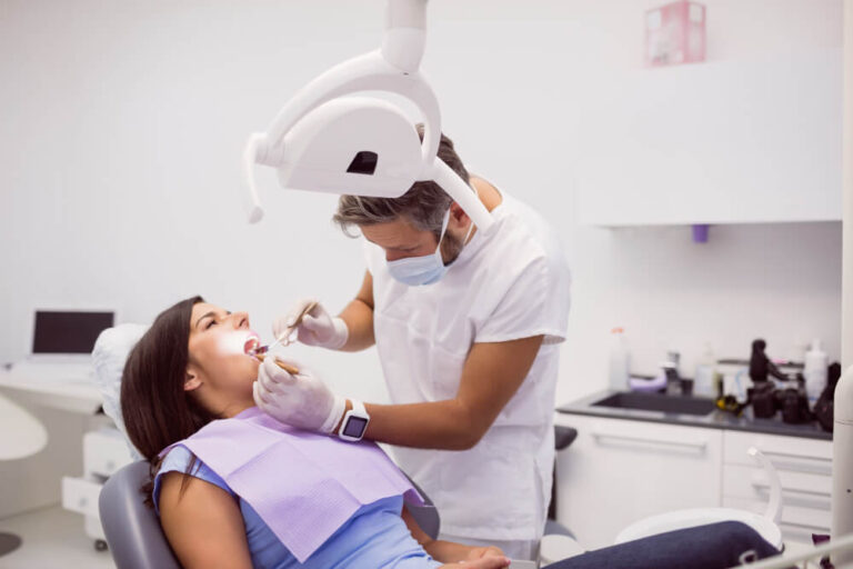 Dentist examining female patient teeth explaining about braces for adults without insurance