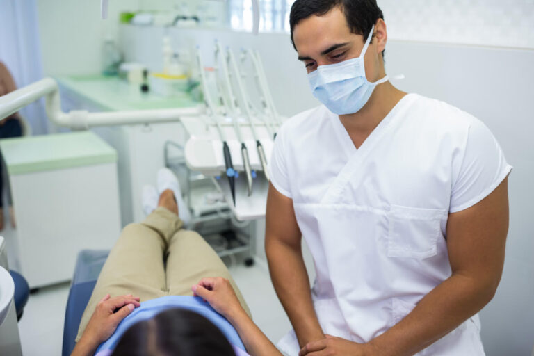 Doctor wearing surgical mask with female patient explaining how to pay for dental work with no money