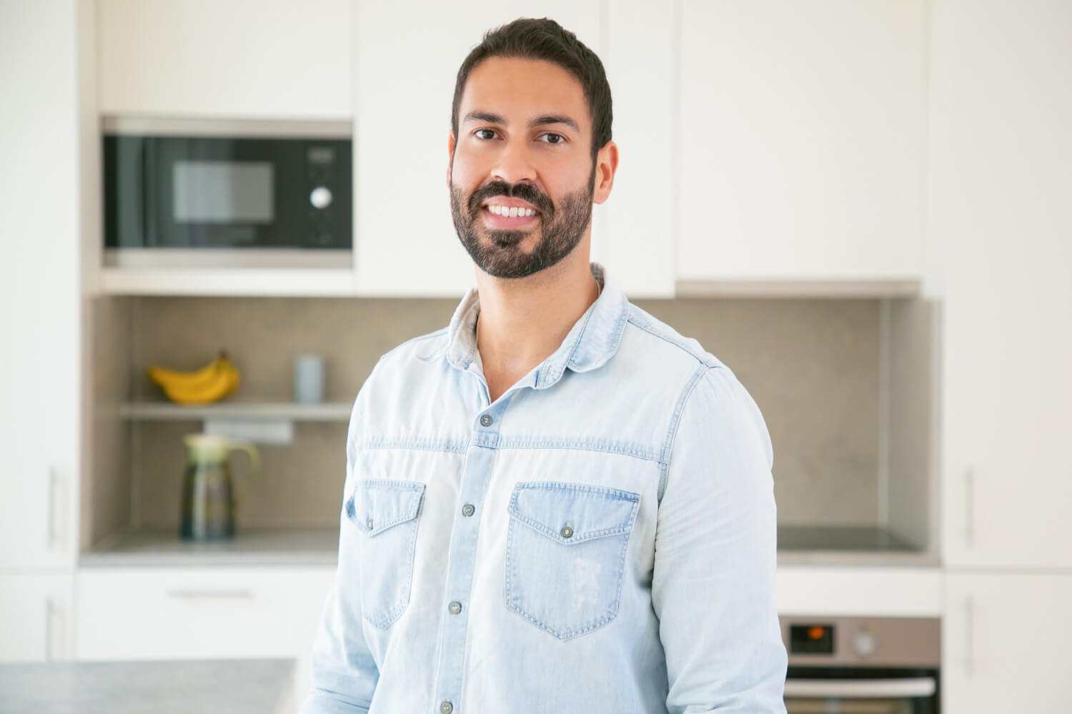 Cheerful attractive dark haired Latin man posing in kitchen