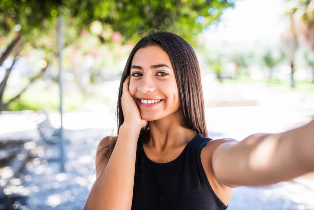 Close-up selfie of a smiling young Latina outside