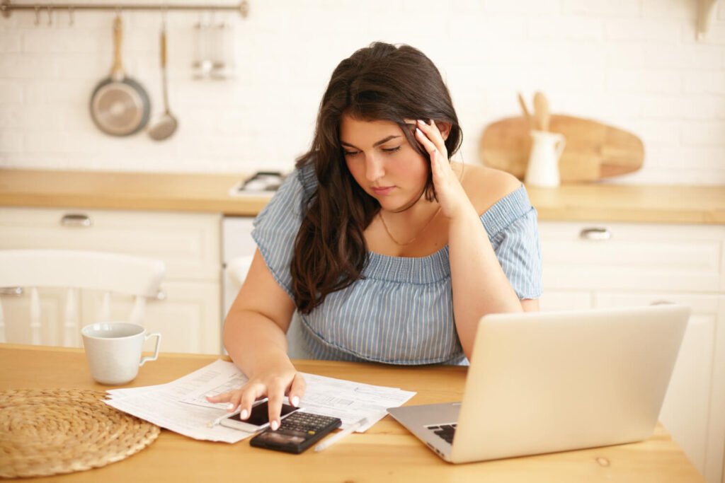 Latin brunette girl sitting indoor worrying about money thinking about what happens if you stop paying your braces