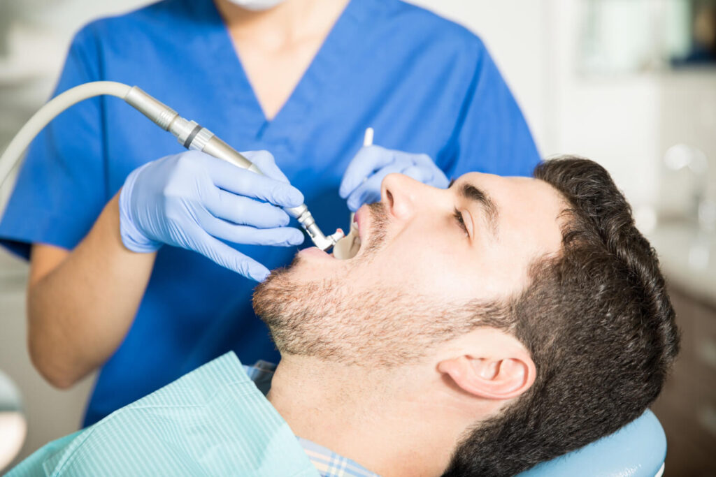 Mid adult man receiving dental treatment from female dentist in clinic learning how to clean teeth with braces