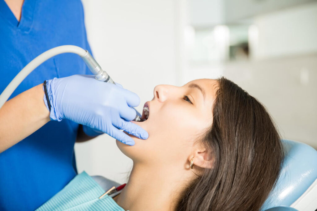 Teenage girl receiving treatment with dental tool from dentist in clinic knowing if can you get your teeth cleaned with braces