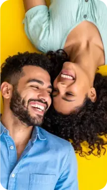mobile-hispanic-couple-smiling-face-to-face-in-front-of-a-yellow-background
